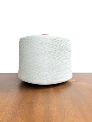 Maruyasu Techne 51 Paper 49 Modal Cone Yarn on a wooden table, showcasing its light color and smooth texture.
